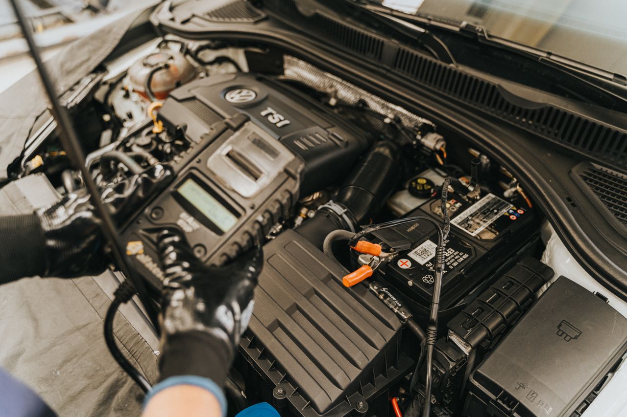 why-choose-us-02 Close-up view of a mechanic diagnosing a Volkswagen engine with specialized equipment.