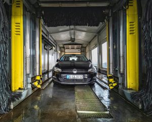 A black car undergoing a thorough cleaning in an automated car wash facility.